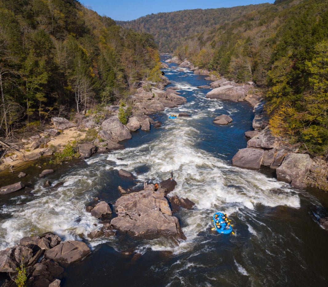A drone shot aerial view of a raft running the hawaii 5 0 wave in Lost Paddle Rapid during a gauley river rafting trip with ACE Adventure Resort in West Virginia.